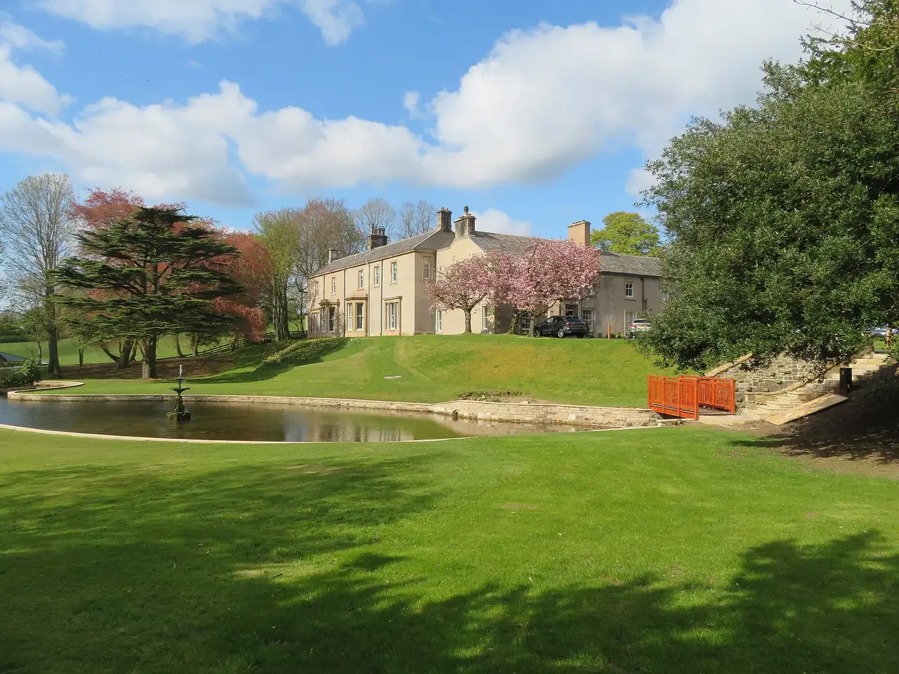 Farlam Hall across its ornamental lake, lawns and specimen trees in spring