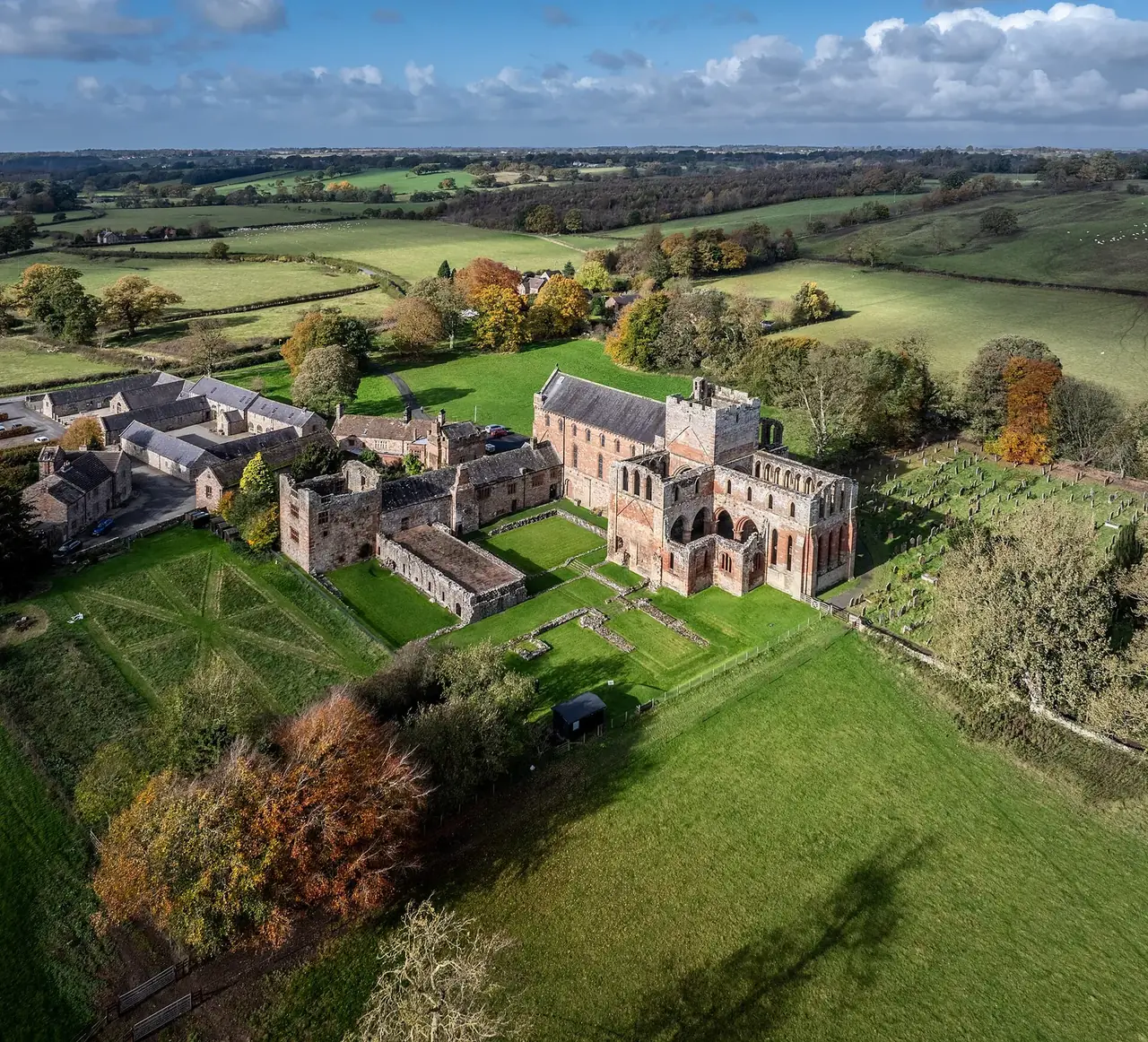 Lanercost Priory from above in October, the trees turning around it